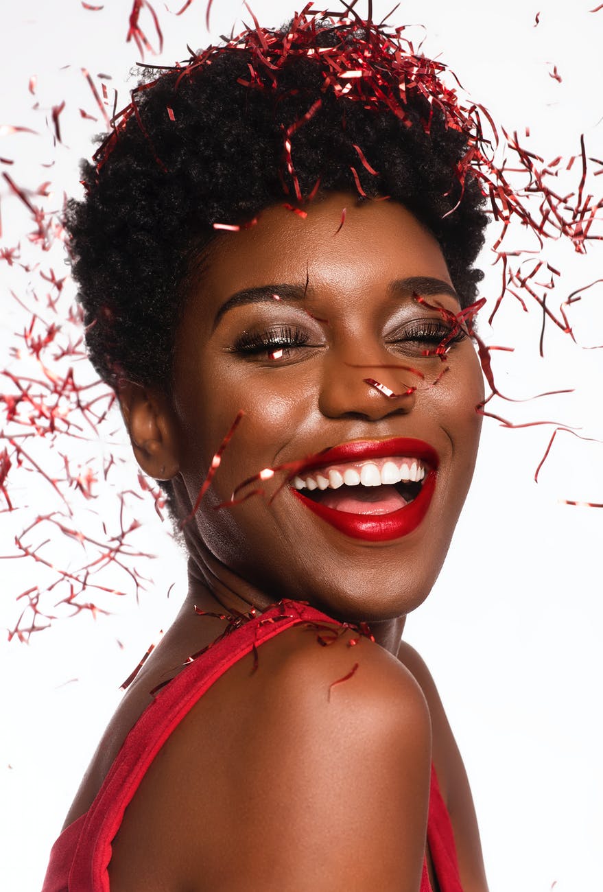 close up photo of smiling woman with her eyes closed posing as confetti drops down her face