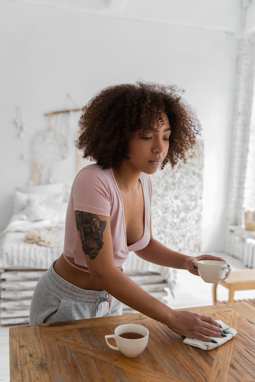 serious black woman wiping table with napkin in morning