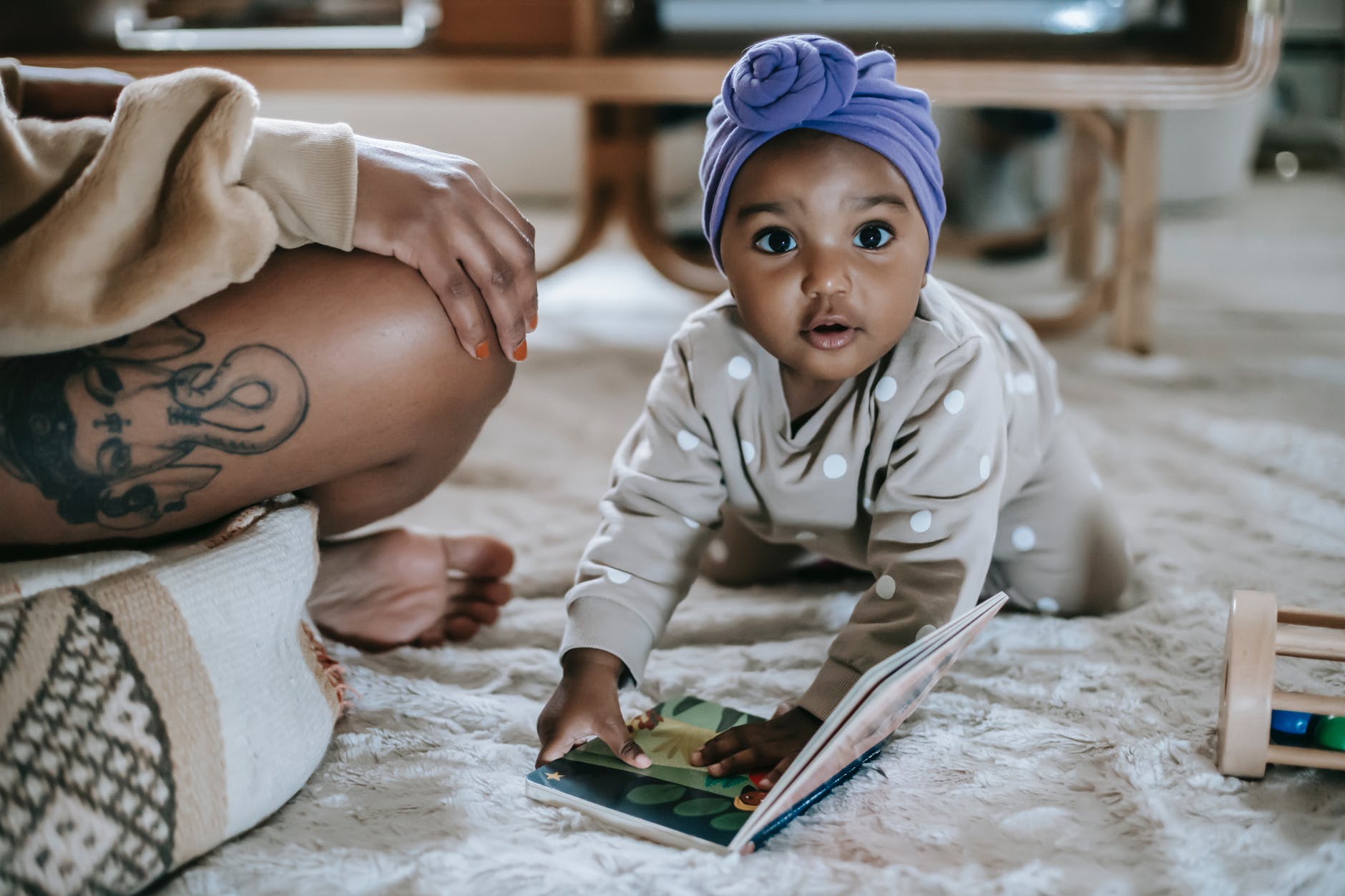 cute black baby with book in room with crop mother
